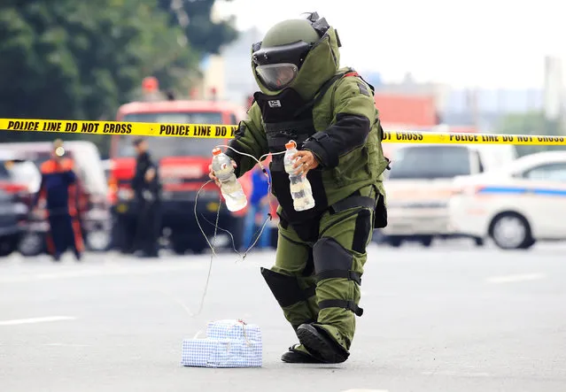 A member of the Philippine National Police (PNP) Explosives and Ordnance Division, wearing a bomb suit, places a bottle of water to diffuse the improvised explosive device during a bomb disposal exercise along a main street in metro Manila, Philippines February 10, 2017. (Photo by Romeo Ranoco/Reuters)