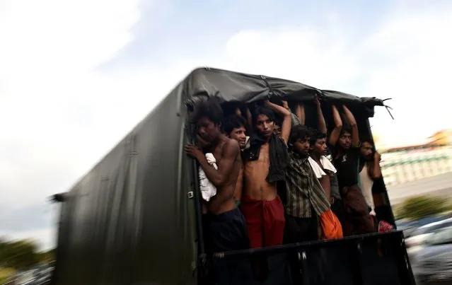  Illegal Bangladeshi migrants stand in a moving police van at the police headquarters in Langkawi on May 11, 2015 after landing on Malaysian shores earlier in the day. Nearly 2,000 boat people from Myanmar and Bangladesh, many thought to be Rohingya, have been rescued off the coasts of Indonesia and Malaysia since May 10. (Photo by Manan Vatsyayana/AFP Photo)