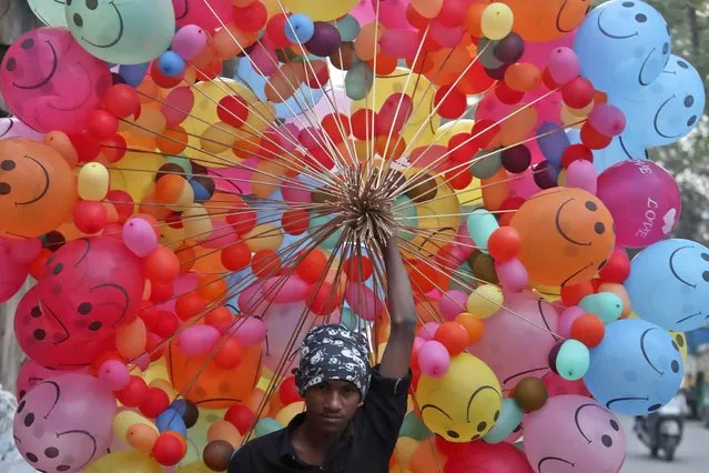 A vendor carries balloons for sale as he walks through a street in Ahmedabad, India, Thursday, December 9, 2021. (Photo by Ajit Solanki/AP Photo)
