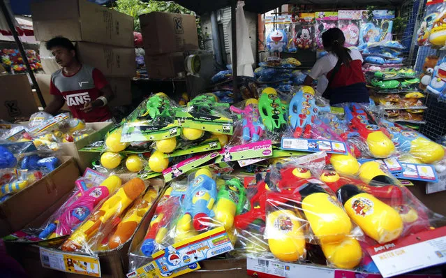 In this April 10, 2016 photo, Thai vendors stand near water pistols as they wait for customers in Bangkok, Thailand. Thailand's military government is putting a dampener on the annual nationwide water fight. Despite Thailand's worst drought in 20 years, the junta says it has no intention of limiting the virtually around-the-clock water throwing that defines the three-day Songkran festival. Instead, it has decided to impose morality measures. Among them, women who show too much skin in wet skimpy attire, or dance too provocatively at raucous street parties could face arrest. (Photo by Sakchai Lalit/AP Photo)