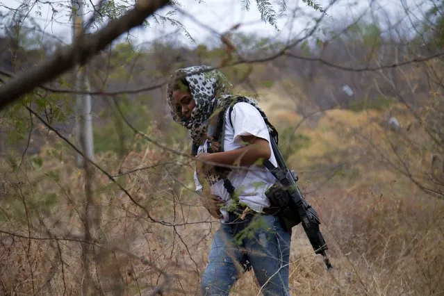 An armed woman who goes by the nickname “La Chola”, and who says she is a member of a female-led, self-defense group, patrols the edge of her town of El Terrero, where it shares a border with the town of Aguililla, in Michoacan state, Mexico, Thursday, January 14, 2021. In the birthplace of Mexico’s vigilante “self-defense” movement, a new group has emerged entirely made up of women, who carry assault rifles and post roadblocks to fend off what they say is a bloody incursion into the state of Michoacán by the violent Jalisco cartel. (Photo by Armando Solis/AP Photo)