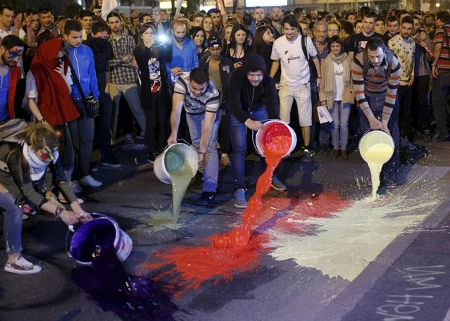 Protesters spill buckets of color paint during a protest against the government, in front of a government building in Skopje, Macedonia April 21, 2016. (Photo by Ognen Teofilovski/Reuters)