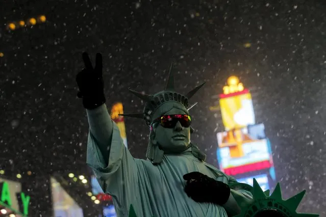 A man is seen posing as the Statue of Liberty in Times Square as snow falls down during the first day of spring in New York, March 20, 2016. (Photo by Eduardo Munoz/Reuters)