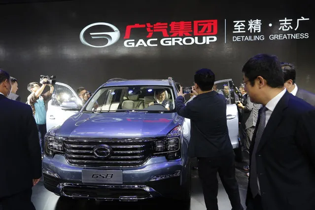 Journalists film Chinese officials examine the Chinese automaker GAC GS8 SUV after it was unveiled at the Beijing International Automotive Exhibition in Beijing, Monday, April 25, 2016. (Photo by Andy Wong/AP Photo)