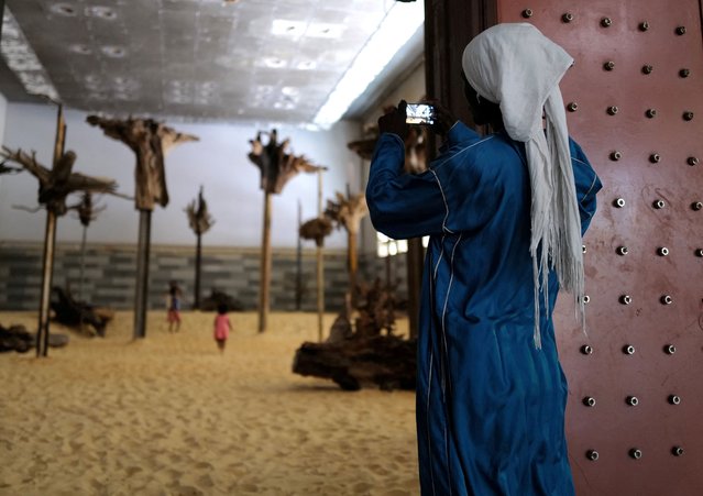 A visitor takes pictures of an art installation by French artist Emmanuel Tussore during the 14th edition of Senegal's Biennale of Contemporary African Art, in Dakar, Senegal, on May 21, 2022. (Photo by Zohra Bensemra/Reuters)