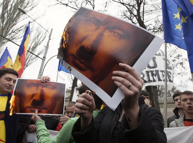 Protesters burn posters depicting Russian President Vladimir Putin at a rally near the Russian Embassy in Chisinau, Moldova, on April 6, 2014. (Photo by Viktor Dimitrov/Reuters)