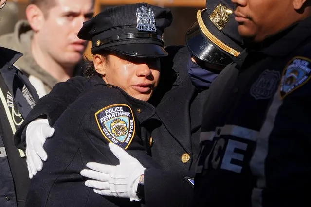 Police officers hug after the casket of NYPD officer Wilbert Mora arrives at a funeral home following a distinguished transfer ceremony, officer Mora was killed while responding to a domestic violence call in the Harlem neighborhood, in New York City, U.S. January 26, 2022. (Photo by Carlo Allegri/Reuters)
