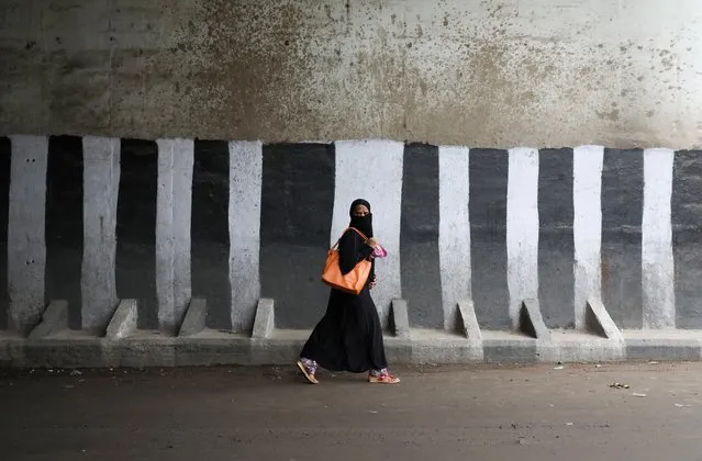 A veiled muslim woman walks across a road in the old quarters of Delhi, July 24, 2019. (Photo by Anushree Fadnavis/Reuters)