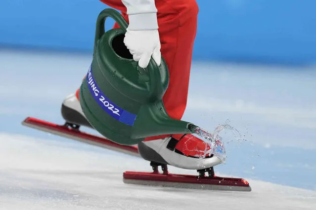 Track officials pour water on the track during the short track speedskating competition at the 2022 Winter Olympics, Wednesday, February 9, 2022, in Beijing. (Photo by Natacha Pisarenko/AP Photo)