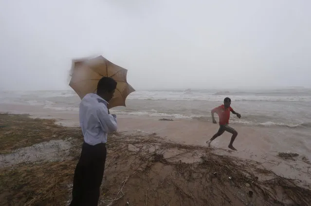 A Sri Lankan man tries to hold his umbrella against the strong wind as a boy runs in Dehiwala on the outskirts of Colombo, Sri Lanka, Saturday, June 8, 2013. (Photo by Eranga Jayawardena/AP Photo)