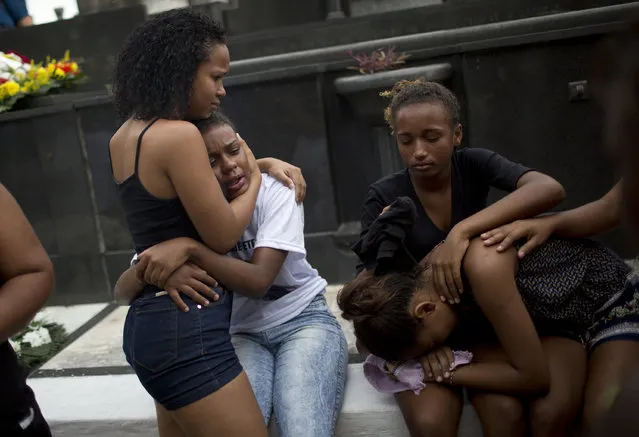 Relatives and friends of Paulo Henrique Oliveira, a 13-year-old who local media said was killed by a stray bullet during a shootout between police and criminals, cry during his burial in Rio de Janeiro, Brazil, Wednesday, April 26, 2017. Hundreds of Brazilians taken the streets of the Alemao slum complex on Tuesday, to protest gun battles between police and gangsters that have killed at least four people and wounded six others, including three policemen. (Photo by Silvia Izquierdo/AP Photo)