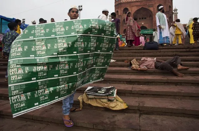 An Indian muslim man sells sheets to use as mat for Eid al-Fitr prayers outside the Jama Masjid mosque in New Delhi, India, Saturday, July 18, 2015. (Photo by Bernat Armangue/AP Photo)