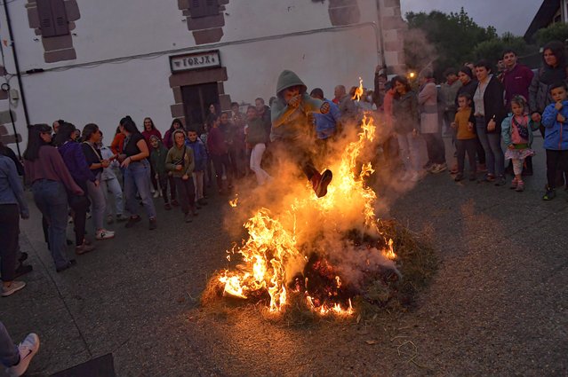 A boy jumps over the fire during the night of San Juan in the Pyrenean village of Arisku, northern Spain, Sunday, June 23, 2024. The night of San Juan, which welcomes the summer season, is an ancient tradition celebrated every year in various towns in Spain. (Photo by Alvaro Barrientos/AP Photo)