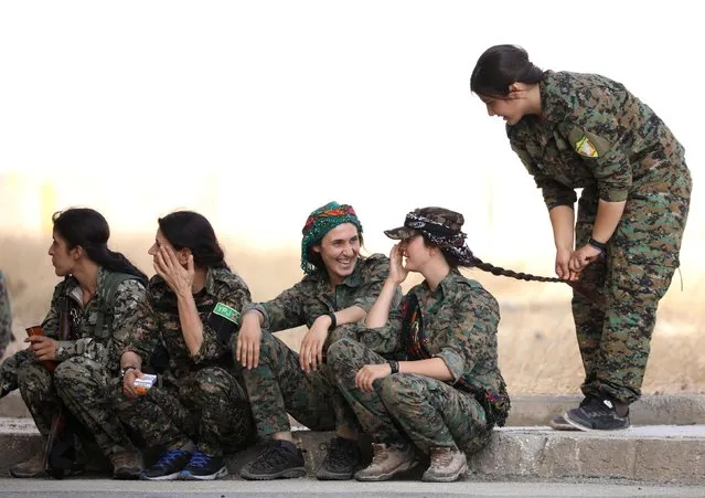 SDF female fighters sit together on a curb in the city of Hasaka, in northeastern Syria, August 2017. (Photo by Rodi Said/Reuters)