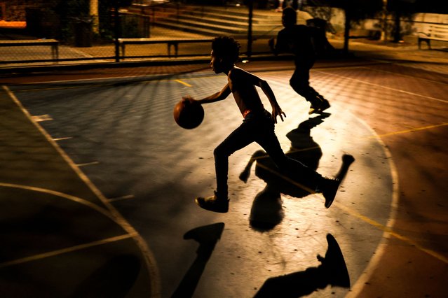 Young boys play basketball at night on a playground of Harlem in New York City on August 14, 2024. (Photo by Charly Triballeau/AFP Photo)