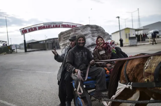 A Turkish family, who earn their life by collecting garbage, ride their cart in front of the Oncupinar crossing gate, near the town of Kilis, in south-central Turkey, on February 11, 2016. (Photo by Bulent Kilic/AFP Photo)