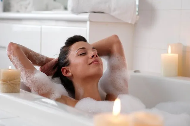 Young woman in bubble bath, smiling. (Photo by LWA/Getty Images)