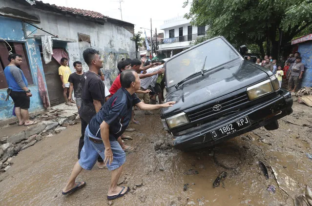 Residents move the wreckage of cars that were swept away by flood in Bekasi, West Java, Indonesia, Friday, January 3, 2020. Severe flooding in greater Jakarta has killed scores of people and displaced tens of thousands others, the country's disaster management agency said. (Photo by Achmad Ibrahim/AP Photo)