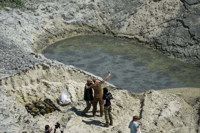 Ukrainian servicemen take selfies as they prepare unexploded Russian ammunition for destruction in the outskirts of Kyiv, Ukraine, Wednesday, June 1, 2022. (Photo by Natacha Pisarenko/AP Photo)