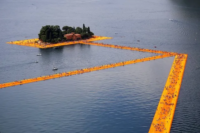People walk on the monumental installation entitled “The Floating Piers” created by artist Christo Vladimirov Javacheff on Iseo Lake, in northern Italy, on June 18, 2016. Some 200,000 floating cubes create a 3-kilometers runway connecting the village of Sulzano to the small island of Monte Isola on the Iseo Lake for a 16-day outdoor installation opening today. (Photo by Marco Bertorello/AFP Photo)