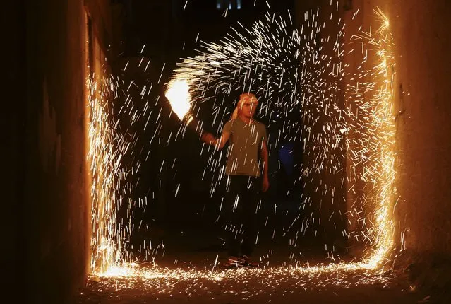 A Palestinian youth plays with fireworks as he celebrates during the Muslim holy month of Ramadan along the alley in Jebaliya refugee camp, Gaza Strip, early Sunday, June 26, 2016. Ramadan is traditionally a time of reflection and prayer, and Muslims are expected to abstain during daylight hours from food, drink, smoking and s*x and to focus on spirituality, good deeds and charity. (Photo by Adel Hana/AP Photo)