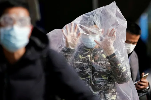 A passenger wearing a mask and covered with a plastic bag walks outside the Shanghai railway station in Shanghai, China, as the country is hit by an outbreak of a new coronavirus, February 9, 2020. (Photo by Aly Song/Reuters)