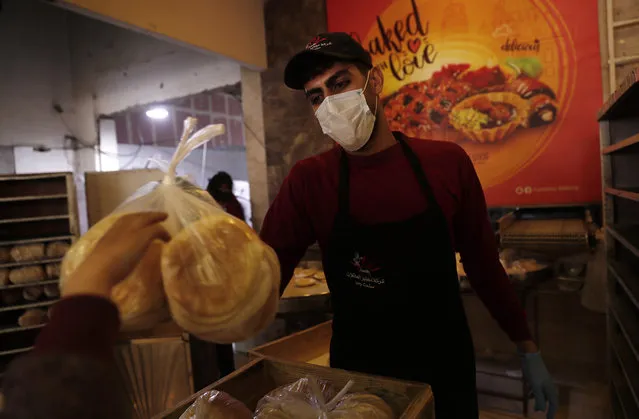 A bakery worker wears a face mask during his work at the family bakery to help prevent the spread of the new coronavirus, in Gaza City, Tuesday, March 10, 2020. For most people, the new coronavirus causes only mild or moderate symptoms, such as fever and cough. For some, especially older adults and people with existing health problems, it can cause more severe illness, including pneumonia. (Photo by Adel Hana/AP Photo)