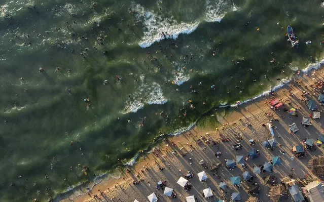 This picture taken on June 10, 2022 shows an aerial view of beachgoers gathering along the Mediterranean seashore in Beit Lahia in the northern Gaza Strip as students start their summer vacation. (Photo by Mohammed Abed/AFP Photo)