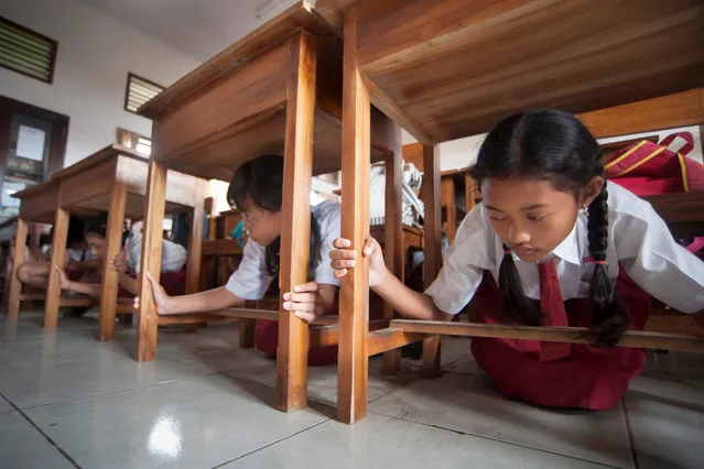 Students protect themselves under a table during tsunami drill at Tanjung Benoa school in Badung, Indonesia Bali resort island, August 15, 2017 in this photo taken by Antara Foto. (Photo by Nyoman Budhiana/Reuters/Antara Foto)