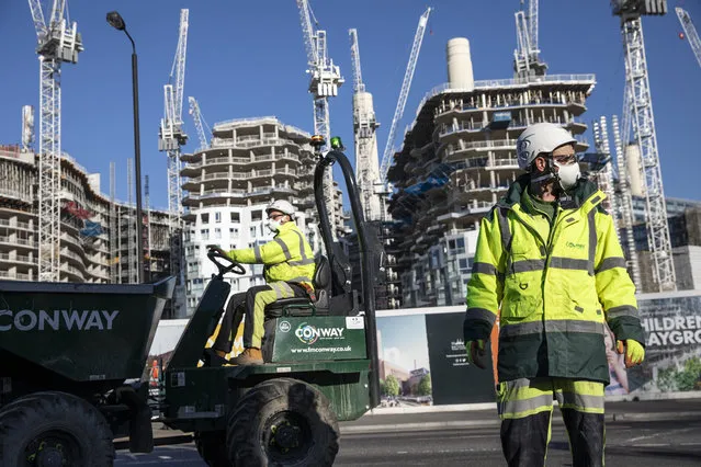 Construction workers wear masks and maintain social distancing as they continue working on Battersea Park Road in Wandsworth, south west London on March 25, 2020 in London, England. British Prime Minister, Boris Johnson, announced strict lockdown measures urging people to stay at home and only leave the house for basic food shopping, exercise once a day and essential travel to and from work. The Coronavirus (COVID-19) pandemic has spread to at least 182 countries, claiming over 18,000 lives and infecting hundreds of thousands more. (Photo by Dan Kitwood/Getty Images)