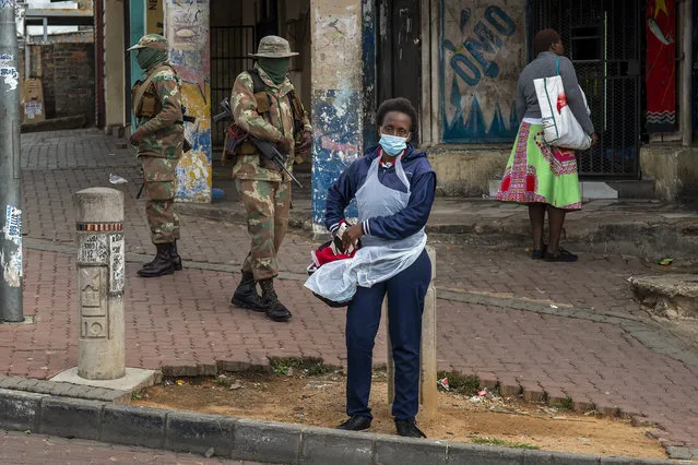 A health worker stands outside a stadium where residents from the Alexandra township in Johannesburg have lined up to be tested for COVID-19 Monday, April 26, 2020. South Africa will began a phased easing of its strict lockdown measures on May 1, although its confirmed cases of coronavirus continue to increase. (Photo by Jerome Delay/AP Photo)
