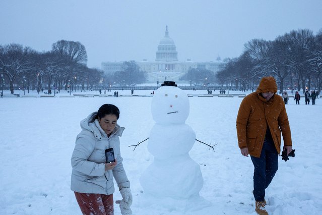 People walk next to a snowman near the U.S. Capitol, on the day of a joint session of the Congress to certify Donald Trump's election, as a winter storm that brought snow, ice and freezing temperatures to a broad swath of the U.S. arrived, in Washington, on January 6, 2025. (Photo by Marko Djurica/Reuters)
