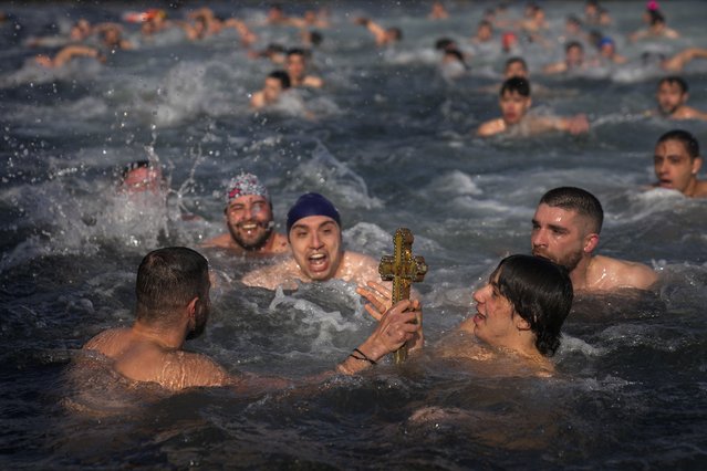 Greek Orthodox faithful hold up a wooden crucifix after being retrieved in the Golden Horn during the Epiphany ceremony in Istanbul, Turkey, Monday, January 6, 2025. (Photo by Khalil Hamra/AP Photo)