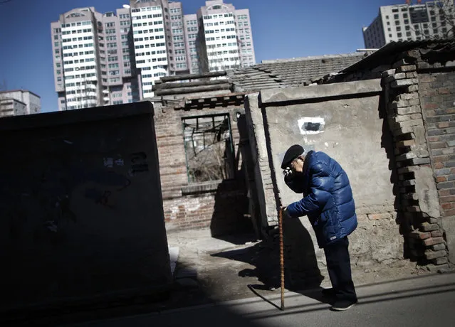 A man walks along a partially demolished house at hutong alleys against the high-rise apartment blocks in Beijing, China Tuesday, March 8, 2011. (Photo by Andy Wong/AP Photo)