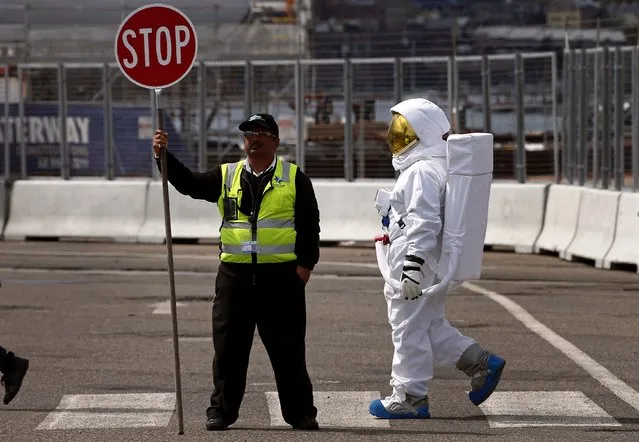 A person dressed as an astronaut walks past a man stopping traffic on a pedestrian crossing outside the Sydney Exhibition Centre September 13, 2014 where the science-fiction convention called “Oz Comic-Con” is currently being held. The two-day convention showcases “pop culture”, and includes appearances by actors from science-fiction movies and television shows. (Photo by David Gray/Reuters)