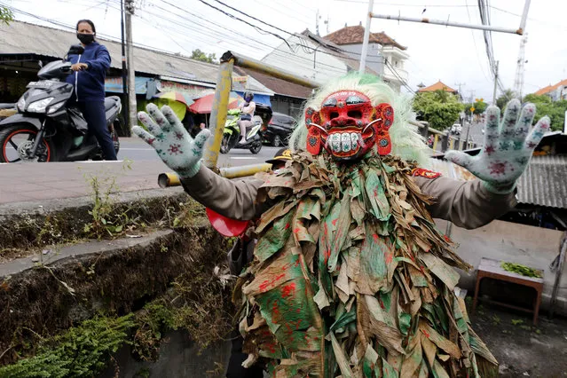 A police officer wearing a Balinese traditional mask, called celuluk, performs as the new coronavirus during a campaign to wear masks as a precaution against the virus outbreak at a market in Bali, Indonesia, Thursday, May 14, 2020. (Photo by Firdia Lisnawati/AP Photo)