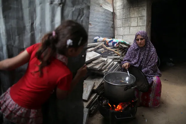 A Palestinian woman cooks on a wood fire at her house during power cut in Beit Lahiya town in the northern Gaza Strip July 6, 2017. (Photo by Mohammed Salem/Reuters)
