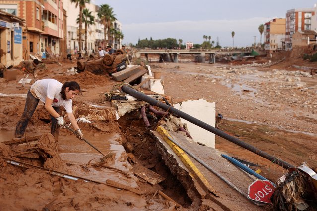 A woman sweeps mud off the street following heavy rains that caused floods, in Paiporta, near Valencia, Spain on November 1, 2024. (Photo by Nacho Doce/Reuters)