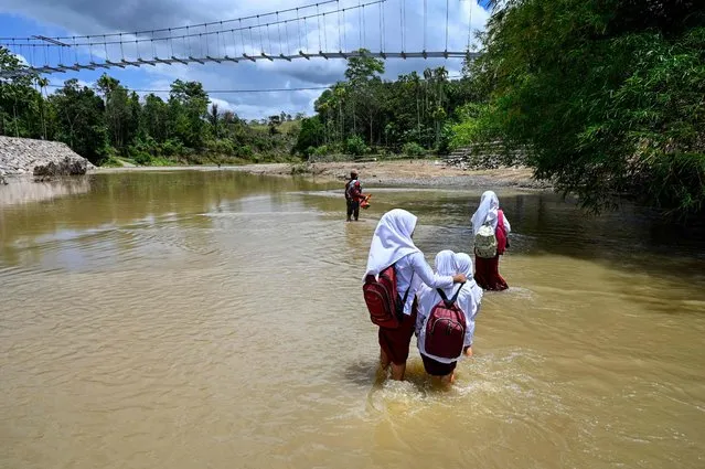 Pupils cross a river from a primary school at Siron village in Kuta Cot Glie, Aceh province on October 4, 2022. (Photo by Chaideer Mahyuddin/AFP Photo)