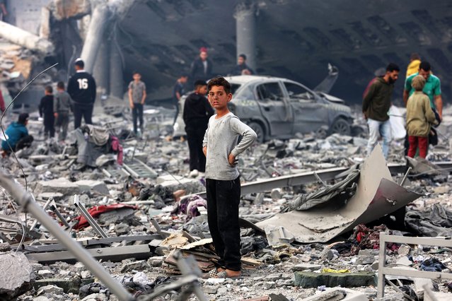 A young boy looks on as Palestinians stand amid the devastation in the yard of a school, a day after it was hit by an Israeli strike, in the al-Tuffah neighbourhood of Gaza City on April 4, 2025. Gaza's civil defence agency said on April 3 that at least 31 people, including children, were killed in the Israeli strike on the school serving as a shelter for Palestinians displaced by the war. (Photo by Omar Al-Qattaa/AFP Photo)