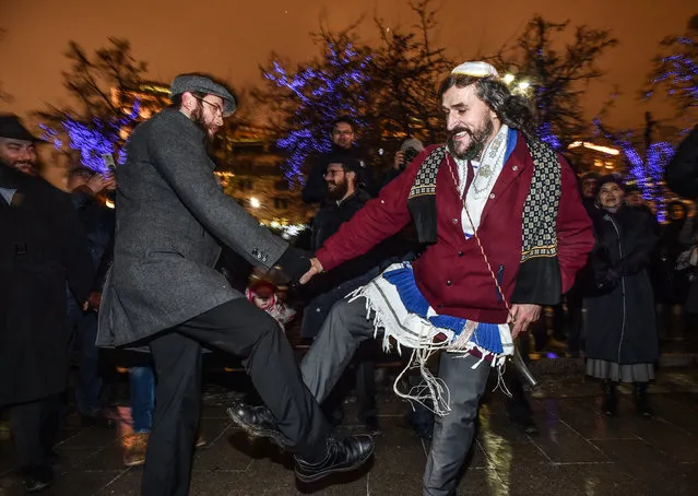 Jewish people dance during Hanukkah celebrations in central Moscow on December 12, 2017. The annual “Festival of Lights” marks the rebellion of Maccabee Jews against the Greeks in 165 BC, which some believers say included a number of miracles pointing to divine providence. (Photo by Vasily Maximov/AFP Photo)