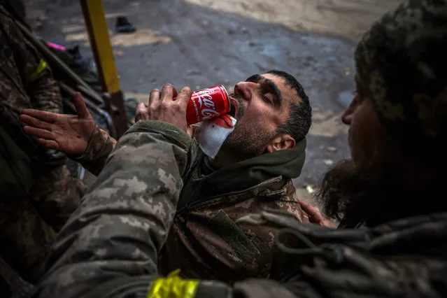 Wounded Ukrainian soldier helps his comrade to drink during their evacuation at a stabilising mobile hospital in the vicinity of Bakhmut, Donetsk region, on December 3, 2022, amid the Russian invasion of Ukraine. (Photo by Anatolii Stepanov/AFP Photo)