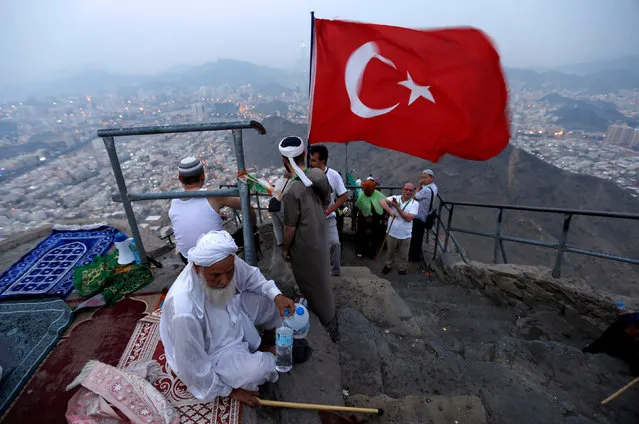 A pilgrim holds Turkey's flag at Mount Al-Noor, where Muslims believe Prophet Mohammad received the first words of the Koran through Gabriel in the Hera cave, ahead of the annual haj pilgrimage in the holy city of Mecca, Saudi Arabia September 7, 2016. (Photo by Ahmed Jadallah/Reuters)