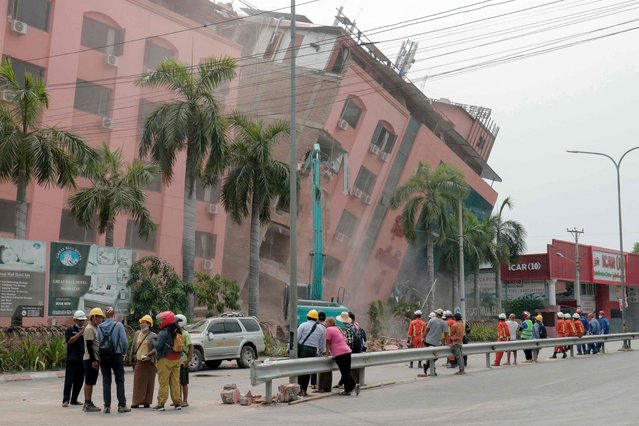 Rescue workers stand on the street next to a collapsed building in Mandalay on April 5, 2025, following the March 28 earthquake. The shallow 7.7-magnitude earthquake on March 28 flattened buildings across Myanmar, killing more than 3,000 people and making thousands more homeless. (Photo by Zaw Htun/AFP Photo)