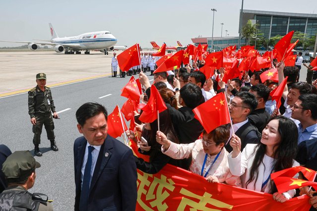 People wave Chinese flags as the plane carrying Chinese President Xi Jinping arrives for a two-day state visit at Hanoi's Noi Bai International Airport in Hanoi on April 14, 2025. His tour of Southeast Asia will also see him visit Malaysia and Cambodia as Beijing seeks to strengthen regional trade ties and offset the impact of huge tariffs unleashed by his US counterpart. (Photo by Athit Perawongmetha/Pool via AFP Photo)