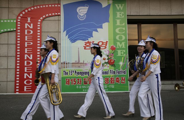 North Korean band members who performed at the Pyongyang International Film Festival walk past a sign at the venue where it was held, on Friday, September 23, 2016, in Pyongyang, North Korea. This year's Pyongyang International Film Festival wrapped up Friday with top honors going to a domestically produced feature about a young woman who devotes herself to raising orphans. (Photo by Wong Maye-E/AP Photo)