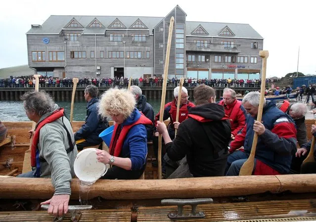 Crew in Britain's first ever full-size reconstructed sea-going Bronze Age boat, bail out water as they prepare to paddle out to sea near to the National Maritime Museum as it makes its maiden voyage on March 6, 2013 in Falmouth, England. (Photo by Matt Cardy)