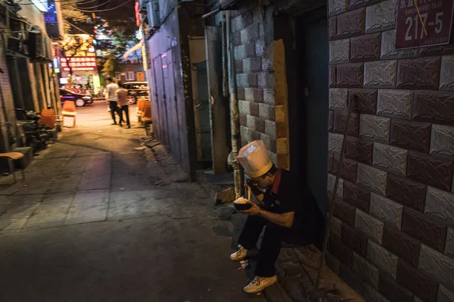 A cook grabs a quick meal outside one of Beijing's numerous eateries on May 26, 2016. Migrants have flooded into the capital city from the country's rural provinces seeking work. (Photo by Michael Robinson Chavez/The Washington Post)