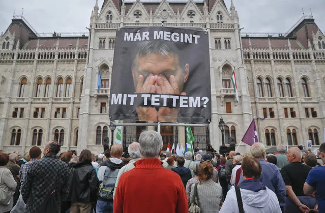 A man holds a poster of Hungarian Premier Viktor Orban that reads “What have I done again” during a protest by opposition parties against Orban's policies on migrants in Budapest, Hungary, Sunday, October 2, 2016. Hungarians vote in a referendum which Prime Minister Viktor Orban hopes will give his government the popular support it seeks to oppose any future plans by the European Union to resettle asylum seekers among its member states. (Photo by Vadim Ghirda/AP Photo)