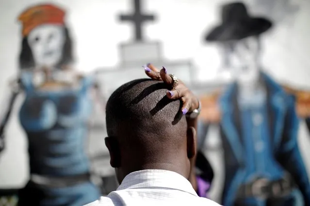 A Mambo, a priestess in the Voodoo religion, touches a believer's head during a ritual at a cemetery in Port-au-Prince, Haiti, November 1, 2020. (Photo by Andres Martinez Casares/Reuters)